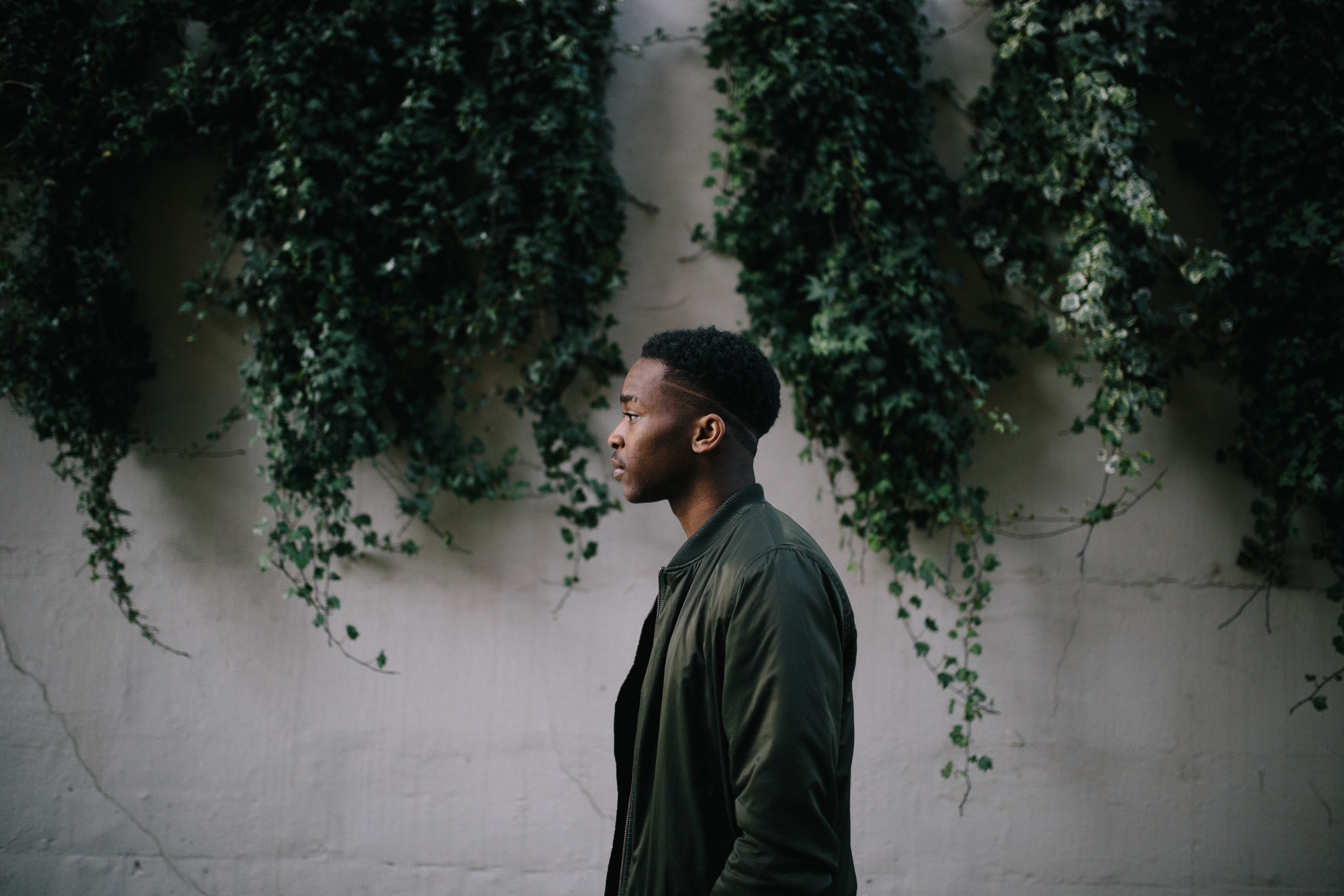 Man Posing by the Wall of Ivy Plants